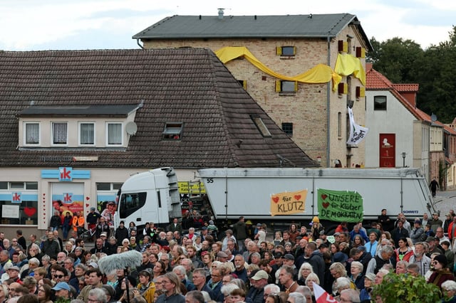 Menschemenge vor einem Kipplader, an dem Plakate hängen "Herzchen für Klütz" und "Herzchen für unsere Demokraten"