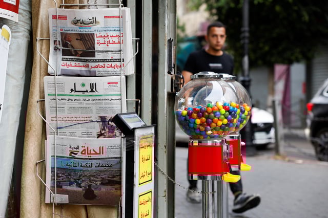 Copies of newspapers are on display outside a shop as a Palestinian man walks by, in the city of Ramallah in the Israeli-occupied West Bank, September 30, 2025. REUTERS/Mohammed Torokman