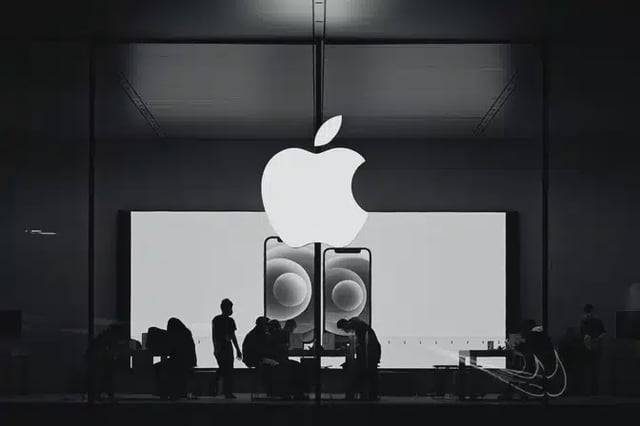 People inside an Apple store with a large Apple logo above.