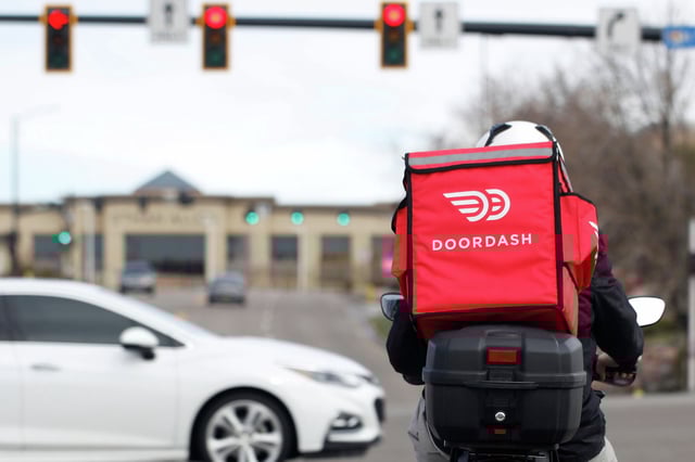 A food delivery rider waits for the traffic light to change Monday, March 30, 2020, in Lone Tree, Colo. The Kroger Co. grocery chain has announced an expanded partnership with delivery service DoorDash to offer Kroger products dropped off to the customer's door. 
