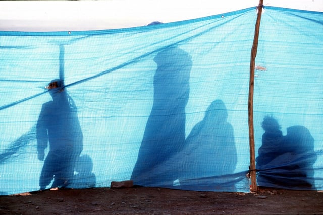 Schattenumrisse von Personen hinter einer blauen Plastikabsperrung