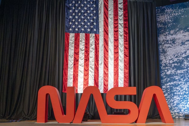 The United States flag hangs behind the NASA logo at the NASA Johnson Space Center in Houston, Monday, Sept. 22, 2025.