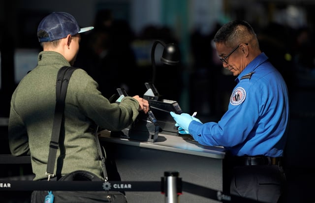 An employee with the Transportation Security Administration (TSA) checks the documents of a traveler at Reagan National Airport in Washington, U.S., January 6, 2019.      REUTERS/Joshua Roberts