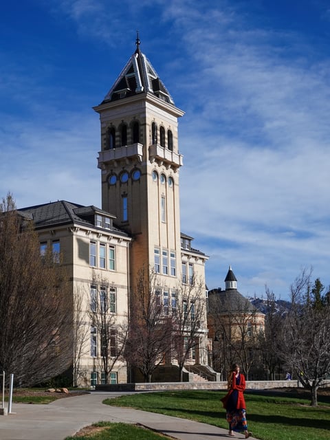Logan, Utah, USA-April 10, 2022:Young woman on her phone walking away from Old Main on the campus of Utah State University.