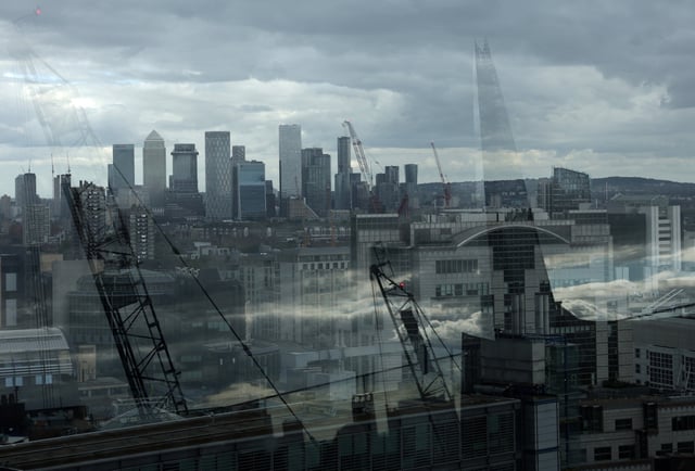 Skyscrapers of the Canary Wharf commercial district are seen with The Shard building and construction cranes reflected in a perimeter glass wall of the viewing area of Garden at 120, in the City of London financial district, in London, Britain, September 23, 2025. REUTERS/Toby Melville