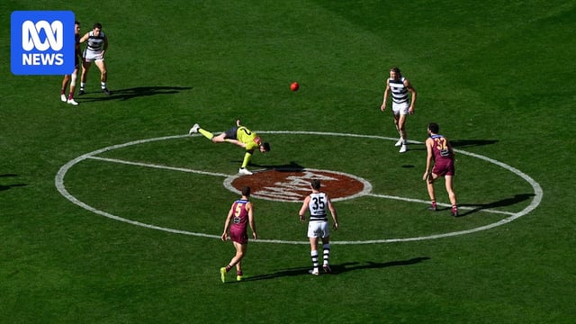 An AFL umpire bounces the ball inside the centre circle