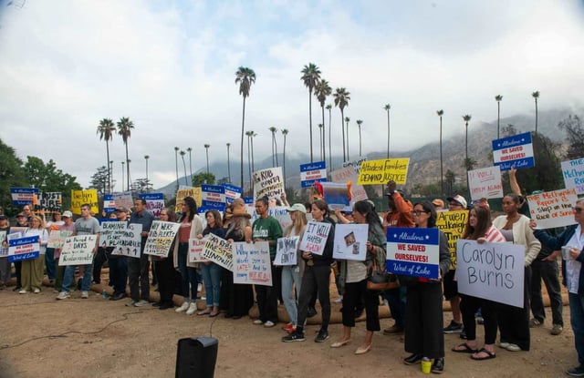Altadena community members, some of which lost homes, hold up signs at the site of a burned Altadena home during Tuesday’s press conference and rally held in response to the release of the McChrystal Group’s “Independent After-Action Report” on the county response to the Jan. fires on September 30, 2025. (Miguel Vasconcellos, Contributing Photographer)
