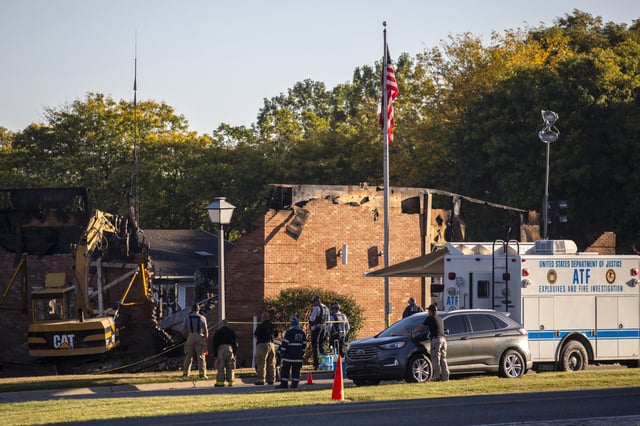 Law enforcement stands nearby as demolition of the remains of the Church of Jesus Christ of Latter-day Saints begins Tuesday in Grand Blanc, Mich.