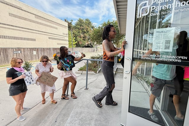 Members of Louisiana Coalition for Reproductive Freedom and supporters arrive at Planned Parenthood on the day they are closing, to deliver cards and flowers to the organization, in New Orleans, Tuesday, Sept. 30, 2025. (AP Photo/Gerald Herbert)