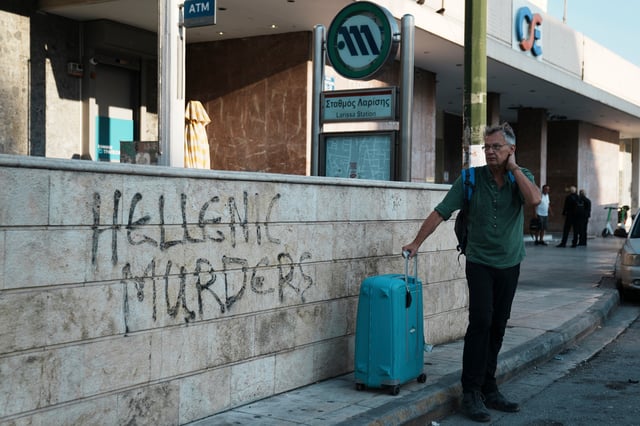 A traveler stands outside the closed main railway station during a nationwide 24-hour strike, as labor unions demand higher wages and the withdrawal of a bill that changes work hours in Athens, Greece, Wednesday, Oct. 1, 2025. (AP Photo/Thanassis Stavrakis)