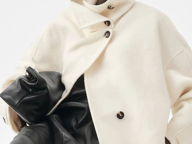 Model wearing a funnel neck coat and leather skirt.