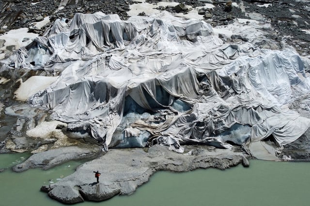 FILE - Matthias Huss, of the Federal Institute of Technology in Zurich and glacier monitoring group GLAMOS, stands at the Rhone Glacier that is partially covered with sheets near Goms, Switzerland, on June 10, 2025. (AP Photo/Matthias Schrader, File)