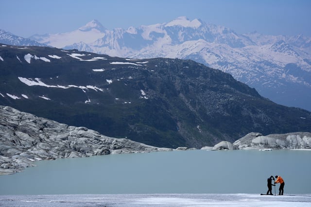 FILE - Matthias Huss, of the Federal Institute of Technology in Zurich and glacier monitoring group GLAMOS, and Monica Ursina Jaeger prepare a camera at the Rhone Glacier near Goms, Switzerland, on June 10, 2025. (AP Photo/Matthias Schrader, File)