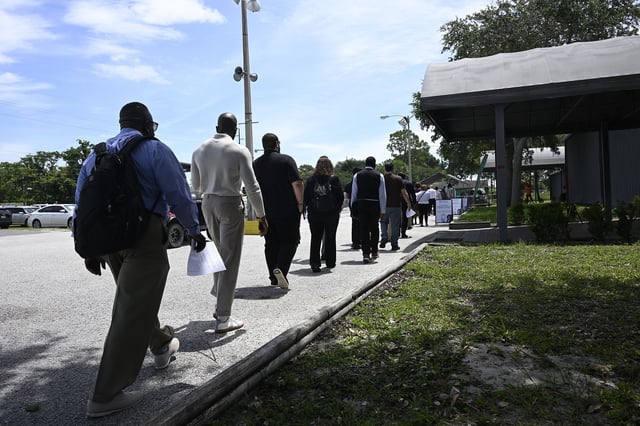 Job seekers walk in line to a job fair at the Central Florida Fairgrounds attended by employers looking to fill openings on July 10 in Orlando.