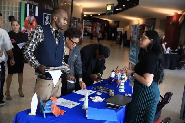 Reuben Granger (L) and other job seekers speak with Nicole Bonilla (R), a recruiter for Margaritaville Beach Resort, during the Mega JobNewsUSA South Florida Job Fair held in the Amerant Bank Arena on September 25, 2025 in Sunrise, Florida. 