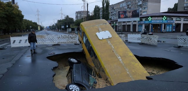 Un bus et une voiture sont visibles dans un trou sur une route à Odessa, en Ukraine, après des pluies torrentielles ayant fait au moins 9 morts, le 1er octobre 2025