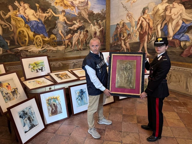 Carabinieri officers hold one of the 21 artworks presumed to be inauthentic and falsely attributed to Salvador Dali, seized during an exhibition in Parma following an investigation by the Rome Public Prosecutor's Office, in Rome, Italy, in this handout picture obtained on October 1, 2025. Carabinieri/Handout via REUTERS    THIS IMAGE HAS BEEN SUPPLIED BY A THIRD PARTY