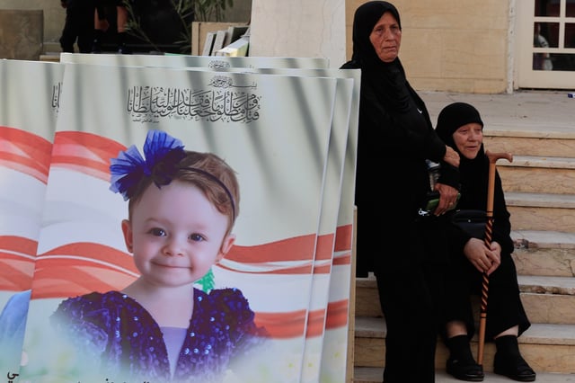 Mourners stand next to the portrait of Silan Charara, killed Sunday in an Israeli drone strike with three family members, during a funeral procession in Bint Jbeil, southern Lebanon, Tuesday, Sept. 23, 2025. (AP Photo/Mohammed Zaatari)