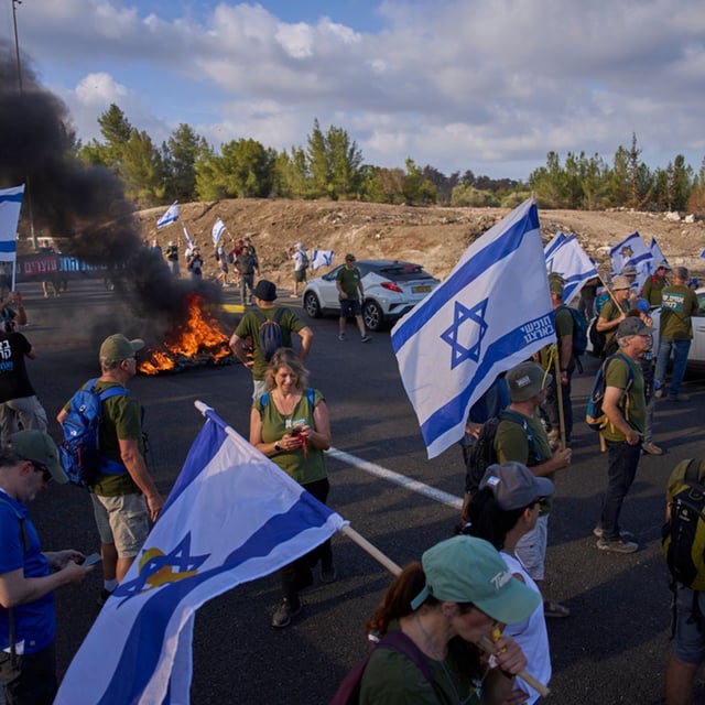 Demonstrators block a road during a protest demanding the immediate release of hostages held by Hamas and calling for the Israeli government to reverse its decision to take over Gaza City and other areas in the Gaza Strip, near Jerusalem, Israel, Sunday, Aug. 17, 2025. (AP Photo/Ohad Zwigenberg)