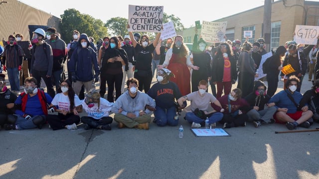Protesters lock arms and block Harvard Street while federal agents stand guard at a gate leading to the U.S. Immigration & Customs Enforcement facility on Sept. 26, 2025, in Broadview. (Stacey Wescott/Chicago Tribune)