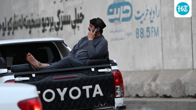 An Afghan man speaks on a mobile phone as he sits on the boot of a vehicle in Kabul on October 1, 2025. (Photo by Wakil KOHSAR / AFP)