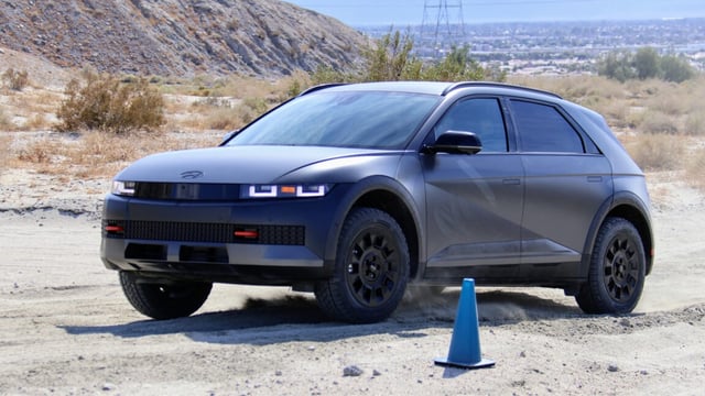 A dark grey Ioniq 5 drives on an off-road course
