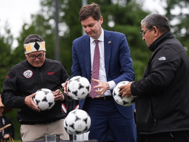 File photo: B.C. Premier David Eby, centre, Musqueam Nation Chief Wayne Sparrow, right, and Squamish Nation councillor Wilson Williams, left, sign soccer balls after announcing a memorandum of understanding regarding hosting FIFA World Cup 26 matches, in Vancouver, on Friday, June 27, 2025. 
