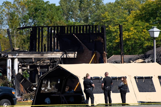 Investigators walk in front of The Church of Jesus Christ of Latter-day Saints in Grand Blanc Township, Mich. where Sunday morning a man rammed his vehicle into the building before opening fire and setting the building ablaze, Tuesday, Sept. 30, 2025. (AP Photo/Ryan Sun)