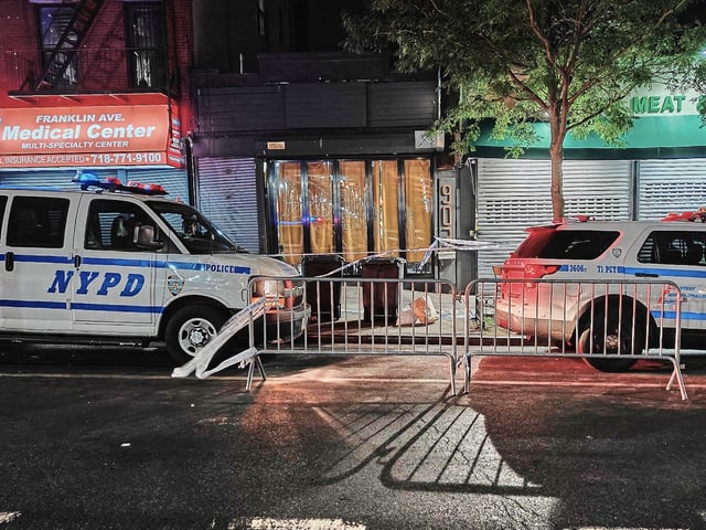 FILE - New York City Police Department vehicles secure the entrance to the Taste of the City Lounge, center, where a shooting took place on Aug. 17 in Brooklyn, New York, Aug. 18, 2025. (AP Photo/Julie Walker, File)
