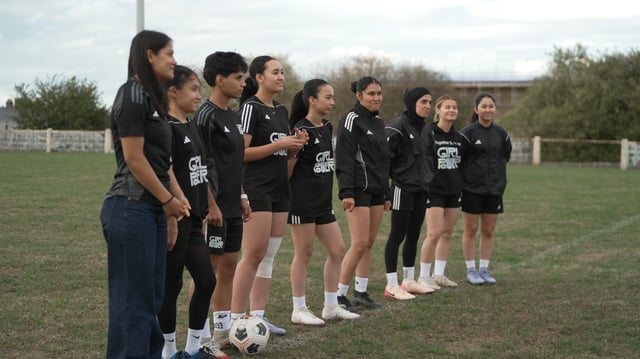 Afghan women's soccer players in exile hold hands on a training pitch in Doncaster, England with former coach and mentor Khalida Popal.