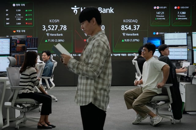 Currency traders work near a screen showing the Korea Composite Stock Price Index (KOSPI), top left, at the foreign exchange dealing room of the Hana Bank headquarters in Seoul, South Korea, Thursday, Oct. 2, 2025. (AP Photo/Ahn Young-joon)