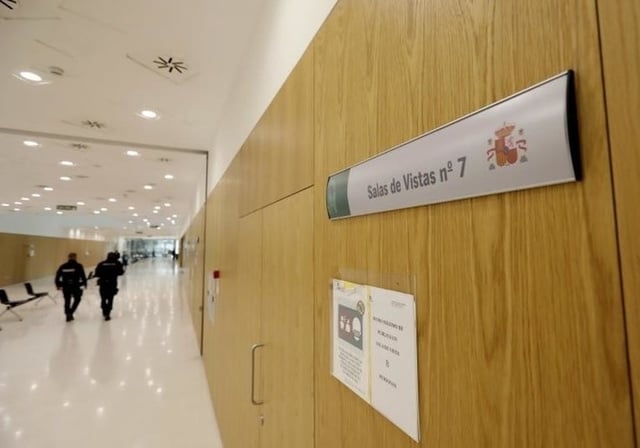 Dos policías nacionales en un pasillo en la que hay una sala de vistas
