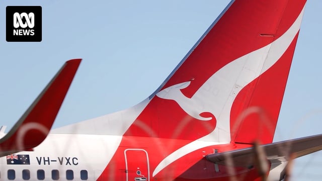 A close-up of the Qantas logo on the tail of one of its planes. The sky behind it is clear.