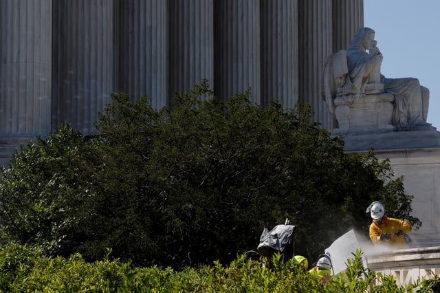 Workers use a pressure washer to clean the plaza in front of the U.S. Supreme Court building in Washington, D.C., U.S. June 28, 2021.  REUTERS/Jonathan Ernst