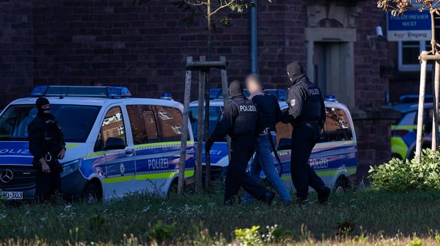 Ein Mann wird von einem Polizisten zu einem Fahrzeug der Bundespolizei geführt