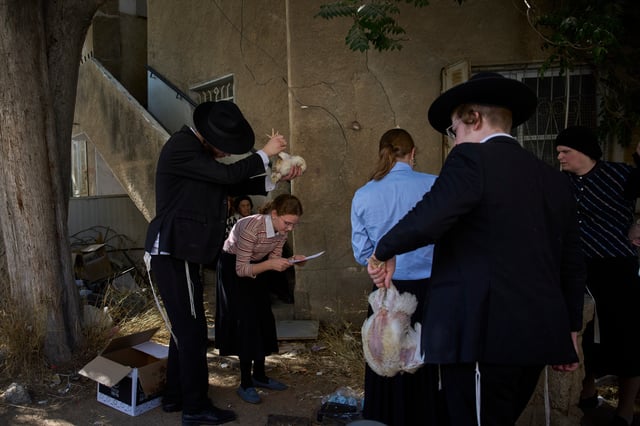 An ultra-Orthodox Jewish man swings a chicken over a woman head in Jerusalem, Monday, Sept. 29, 2025, as part of the Kaparot ritual before the Jewish holiday of Yom Kippur. (AP Photo/Ohad Zwigenberg)