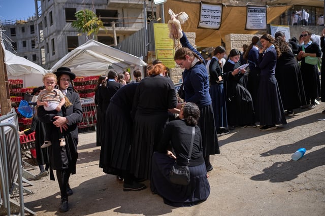 An ultra-Orthodox Jewish woman swings a chicken over head in Jerusalem, Monday, Sept. 29, 2025, as part of the Kaparot ritual before the Jewish holiday of Yom Kippur. (AP Photo/Ohad Zwigenberg)