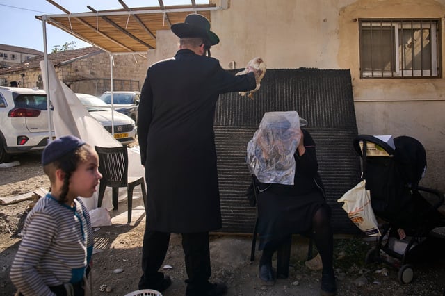 An ultra-Orthodox Jewish man swings a chicken over a woman head in Jerusalem, Monday, Sept. 29, 2025, as part of the Kaparot ritual before the Jewish holiday of Yom Kippur. (AP Photo/Ohad Zwigenberg)