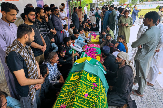People sit around the bodies of three victims, who were killed in Wednesday's clashes between police and protestors, before their funeral prayers, in Muzaffarabad, the capital of Pakistani controlled Kashmir, Thursday, Oct. 2, 2025. (AP Photo/M.D. Mughal)
