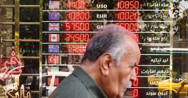 A man walks past an electronic board displaying currency exchange rates in Ferdowsi Square in Tehran on earlier this week. AFP