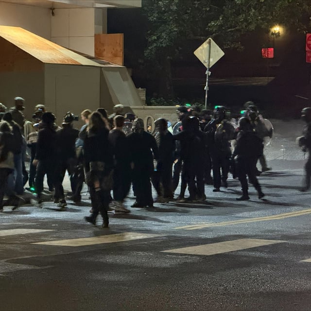Protesters and federal officers can be seen outside the ICE facility in South Portland on Monday night, Sept. 29, 2025. (Victor Park/KATU)