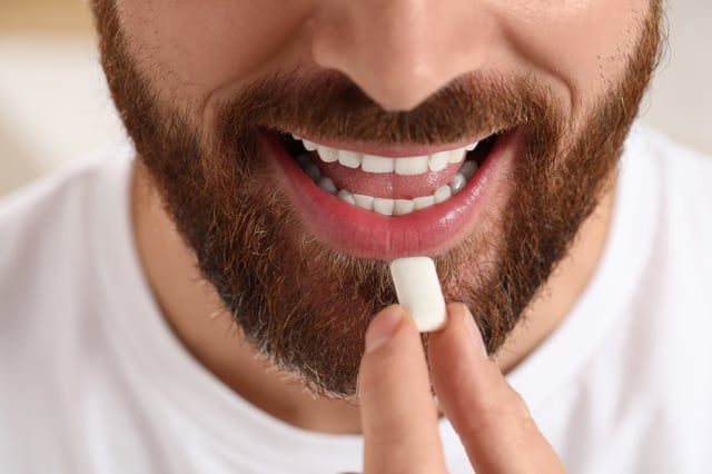 Man with chewing gum on blurred background, closeup