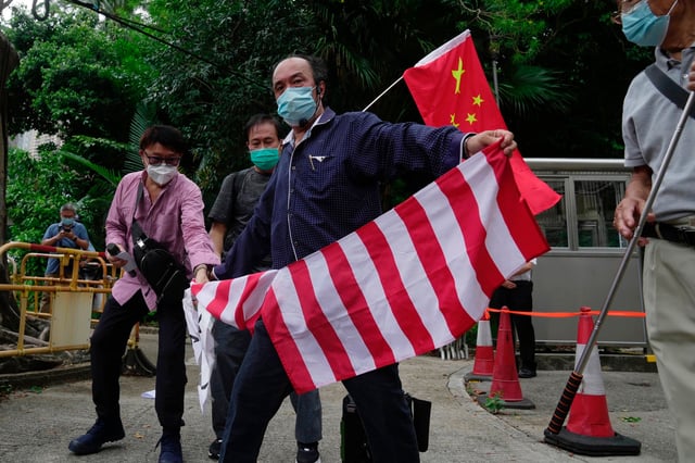 Pro-China supporters tear the U.S. flag during a protest outside the Consulate General of the United States in Hong Kong, Wednesday, Aug. 3, 2022. U.S. House Speaker Nancy Pelosi arrived in Taiwan late Tuesday, becoming the highest-ranking American official in 25 years to visit the self-ruled island claimed by China, which quickly announced that it would conduct military maneuvers in retaliation for her presence. (AP Photo/Kin Cheung)