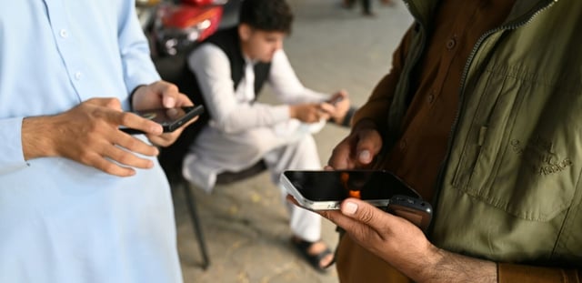 Des Afghans consultent leurs téléphones portables, le 1er octobre 2025 à Kaboul