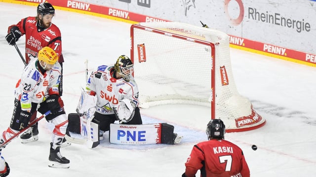 Eishockey-Spieler der Fischtown Pinguins aus Bremerhaven verteidigen ihr Tor gegen die Kölner Haie, Torwart Kristers Gudlevskis schaut hinter sich zum Puck, der an seinem Tor vorbeigerutscht ist.