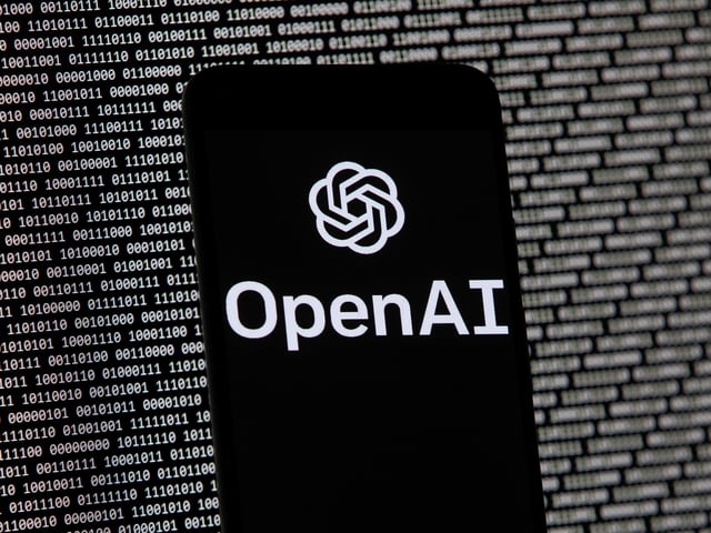 FILE - The OpenAI logo appears on a mobile phone in front of a computer screen with random binary data, March 9, 2023, in Boston. (AP Photo/Michael Dwyer, File)