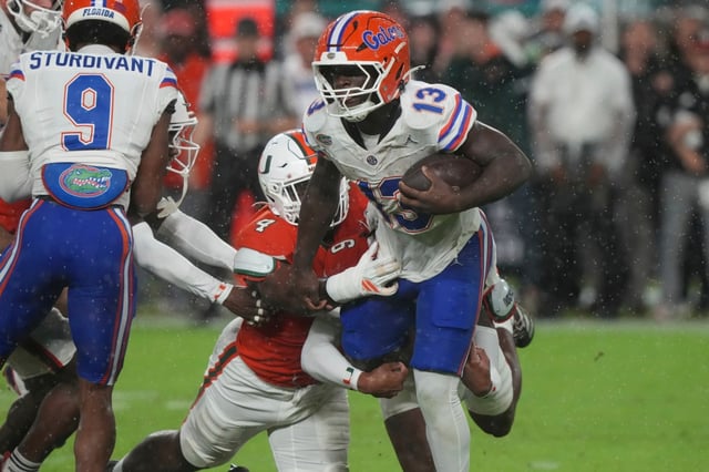 Florida running back Jadan Baugh (13) is tackled by Miami defensive lineman Rueben Bain Jr. (4) during the first half of an NCAA college football game, Saturday, Sept. 20, 2025, in Miami Gardens, Fla. (AP Photo/Marta Lavandier)