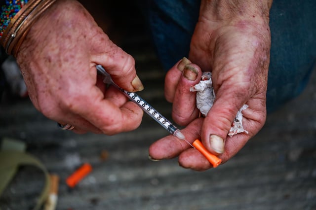 Rebecca Byrd, 58, puts the cap back on the needle after using fentanyl in Willow Alley in San Francisco. The city is pushing for more sober housing for homeless people. 