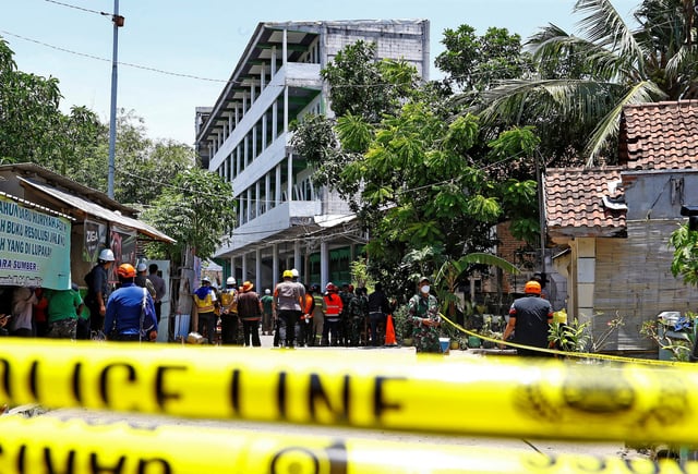 Rescuers gather near the site of a building collapse on Monday, where people remained trapped according to disaster mitigation agency, as the search and rescue operations continue at Al Khoziny Islamic boarding school in Sidoarjo, East Java province, Indonesia, October 2, 2025. REUTERS/Dipta Wahyu