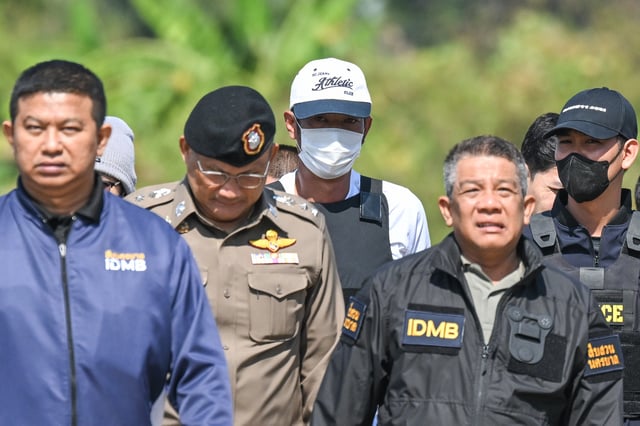 Thai police officers escort Ekkalak Pheanoi, center, the accused in the shooting of Cambodian politician Lim Kimya, after he was deported from Cambodia, in Bangkok, Thailand, on Jan. 11, 2025. (AP Photo/Panumas Sanguanwong)